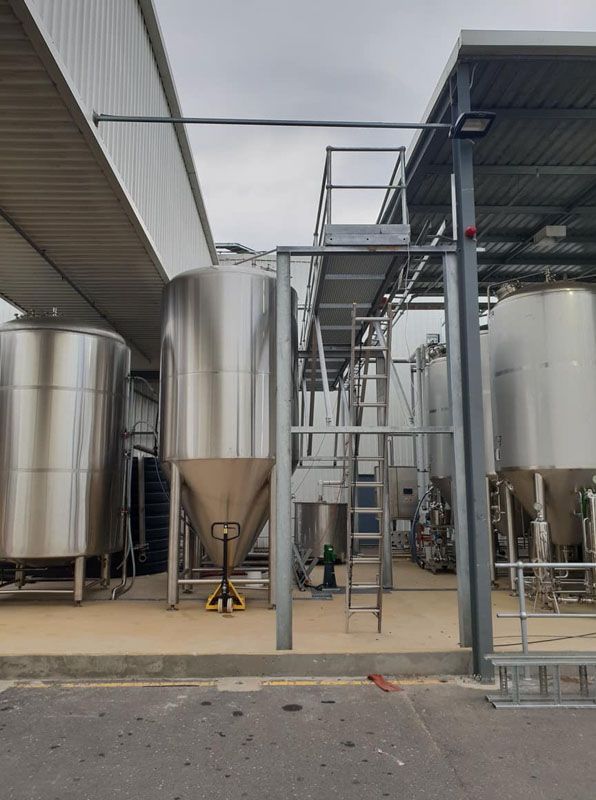 A lot of stainless steel tanks are outside of a building