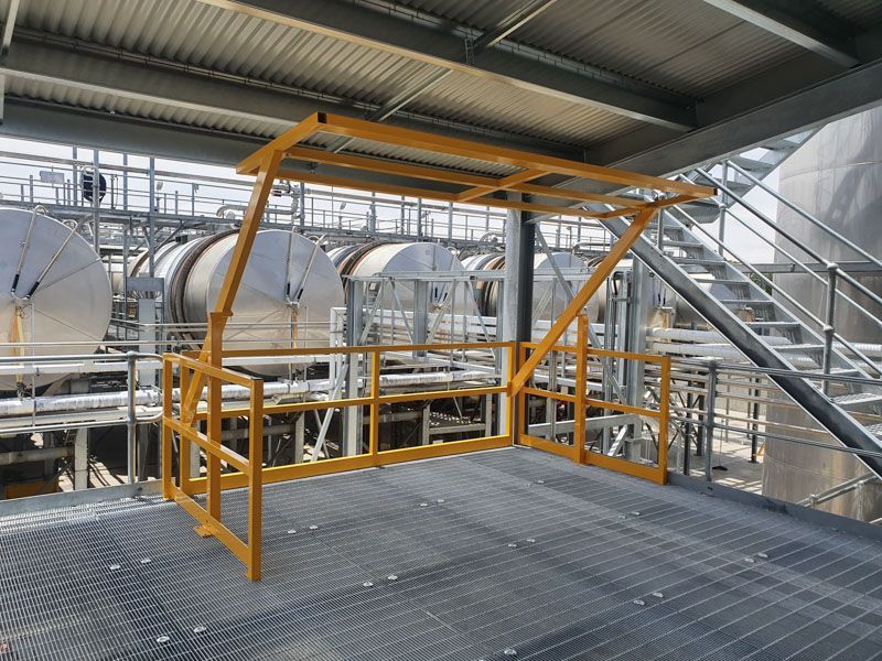 A yellow railing is sitting on top of a metal platform in a factory.