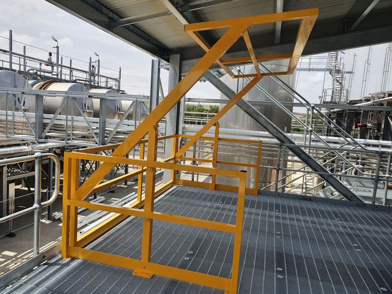 A metal staircase with a yellow railing in a factory