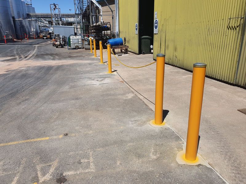 A row of yellow poles are lined up on the side of a road