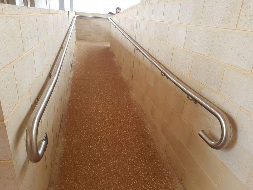 A staircase with a stainless steel railing and a brick wall.