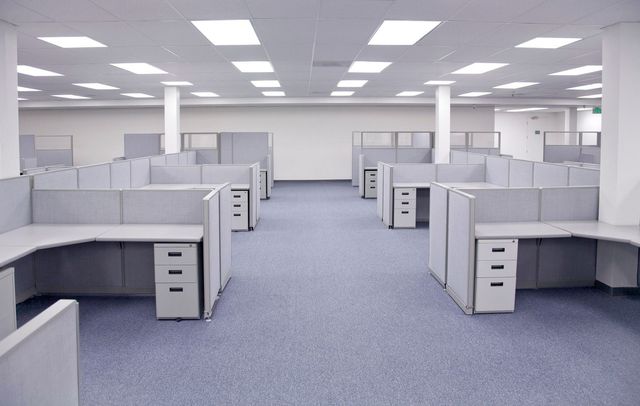 An office with a lot of desks and chairs and a conference room.