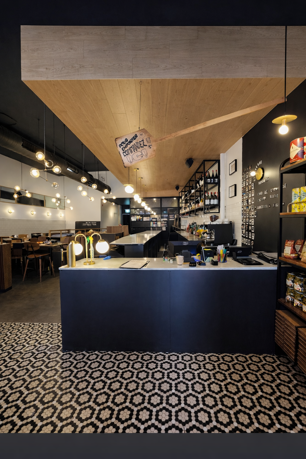 Intérieur de café moderne avec un comptoir bleu, un sol carrelé à motifs et des suspensions lumineuses chaleureuses.