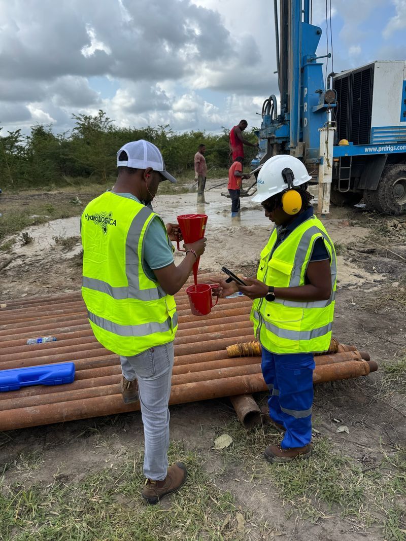 Two workers in safety vests inspecting red pipe fittings at an outdoor work site