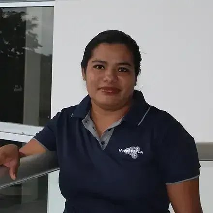 Person in a navy polo shirt leaning on a railing indoors, with a slight smile.
