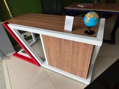 Mostrador largo de madera con base de metal negro en una habitación con azulejos blancos, con un pequeño banco cerca.