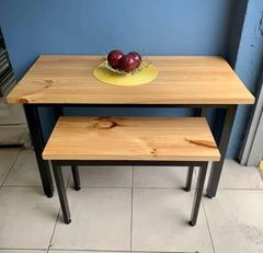 Mesa de comedor de madera con patas de metal negro en una habitación minimalista.
