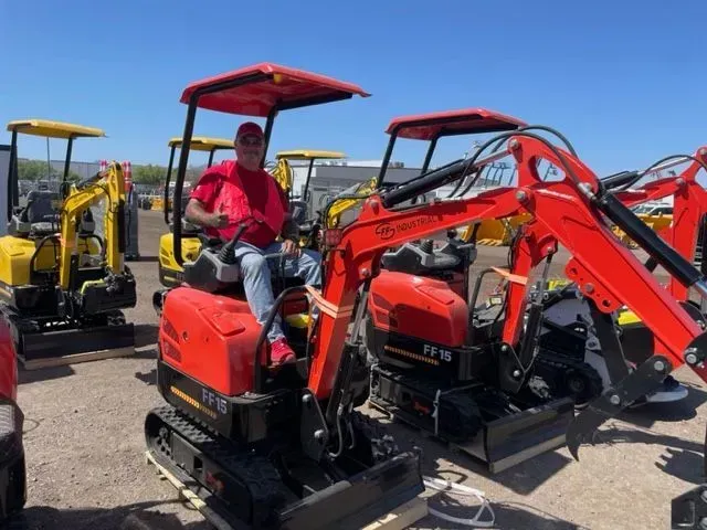 A man is sitting on a small red excavator