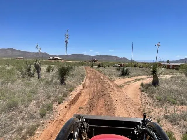 A red vehicle is driving down a dirt road.
