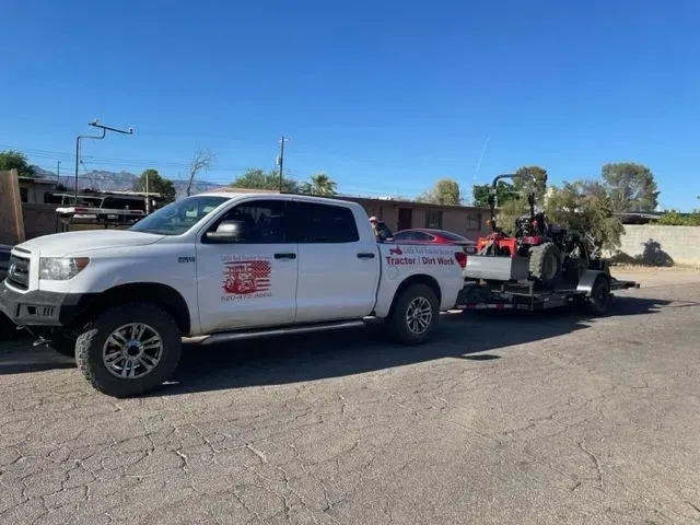 A white truck is towing a red vehicle on a trailer.