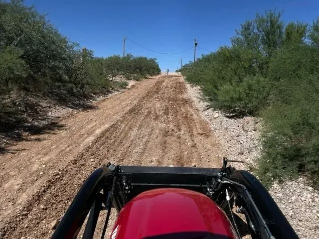 A red helmet is on the back of a vehicle on a dirt road