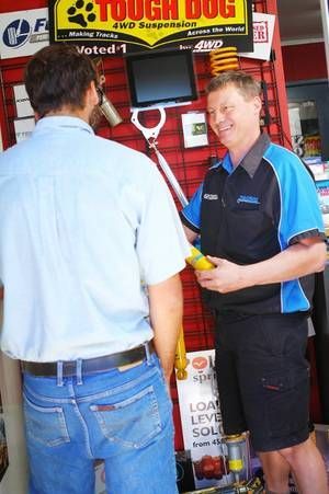 Two men talking at a booth with a red vending machine and a “TOUGH DOG” sign