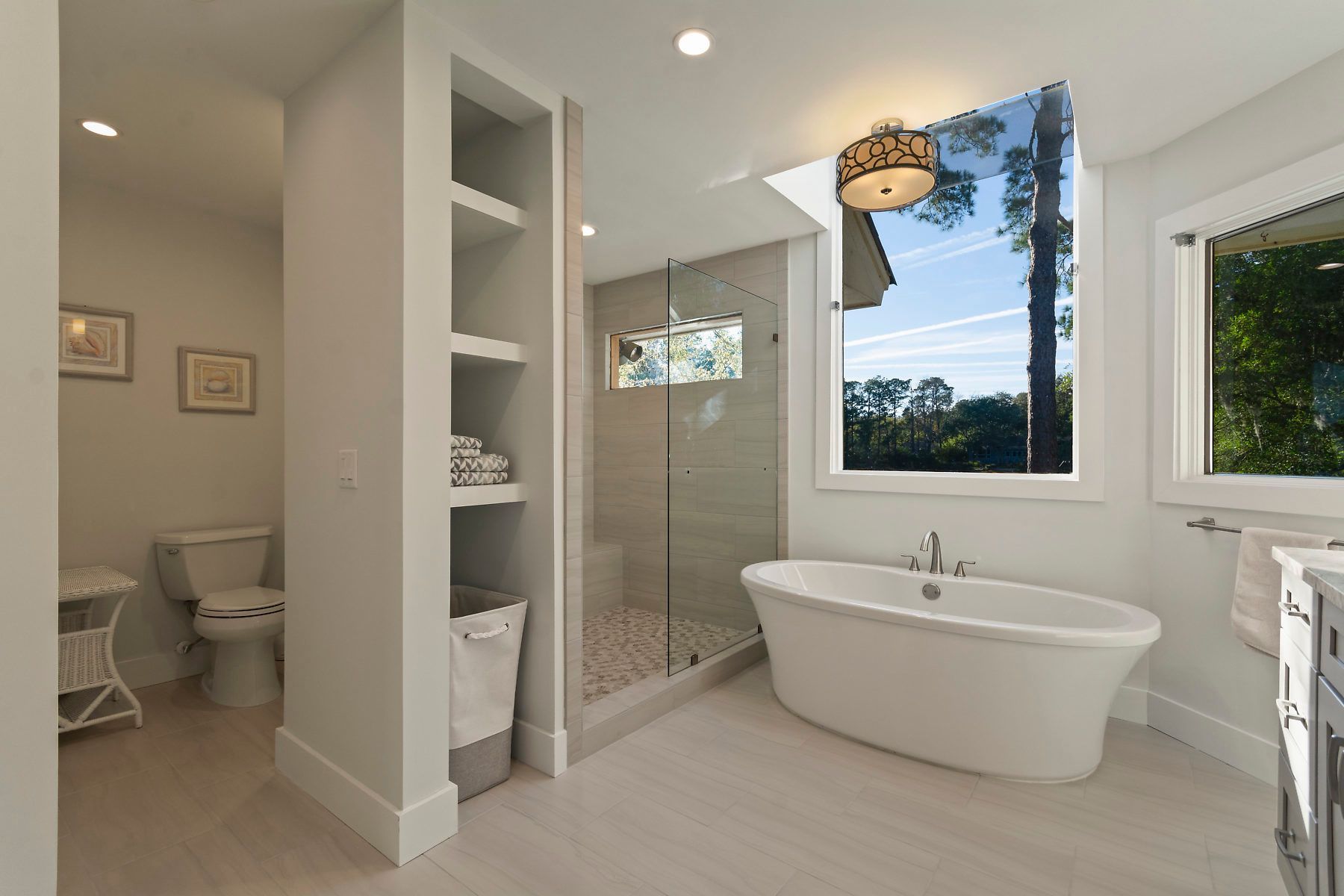 Spacious white walk-in closet with central island and built-in storage. Soft lighting, hardwood floor.
