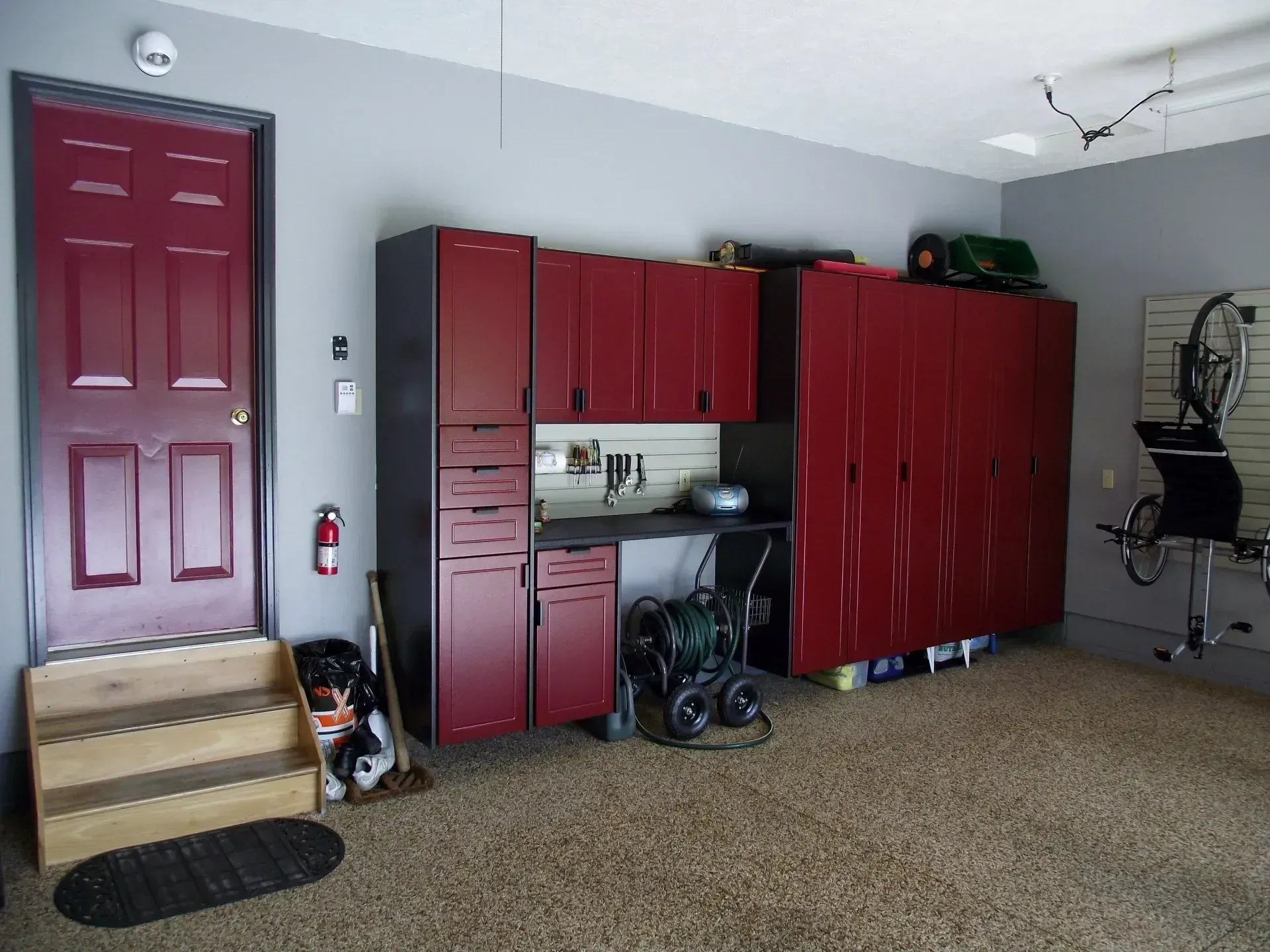 Garage interior with red cabinets, a door, and storage on the wall.