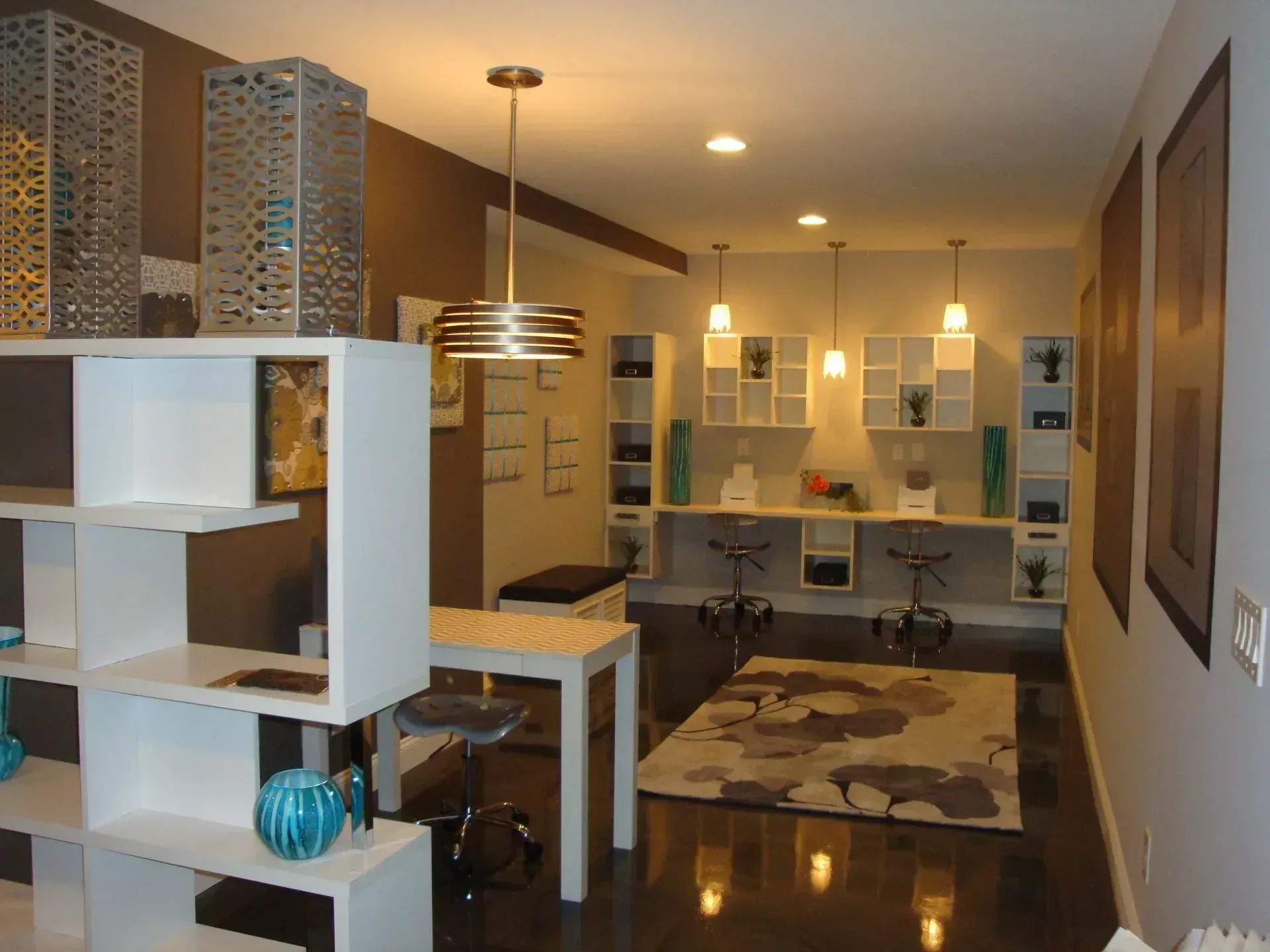 Interior of a modern studio with white shelving, pendant lights, and dark brown accent wall.