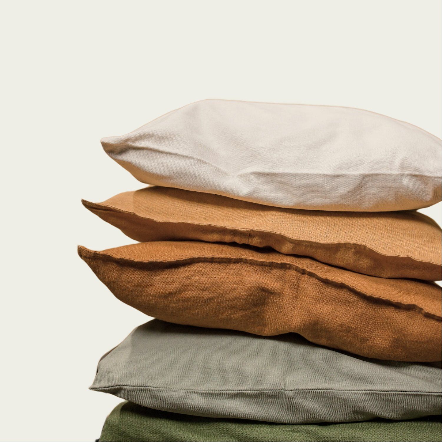 Stack of textured square throw pillows in various earth tones.