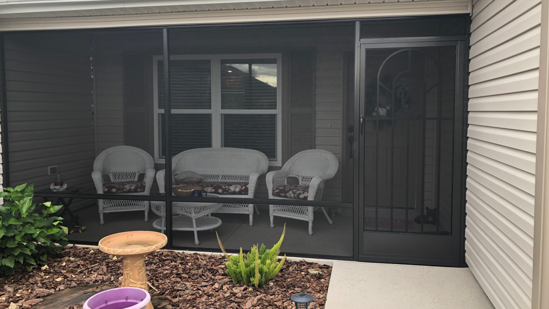 A screened in porch with a couch and chairs