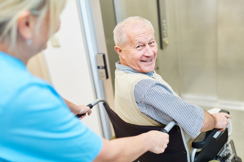 A Nurse Is Helping An Elderly Man In A Wheelchair — Southern Districts Physiotherapy & Sports Injuries Clinic In Albion Park, NSW