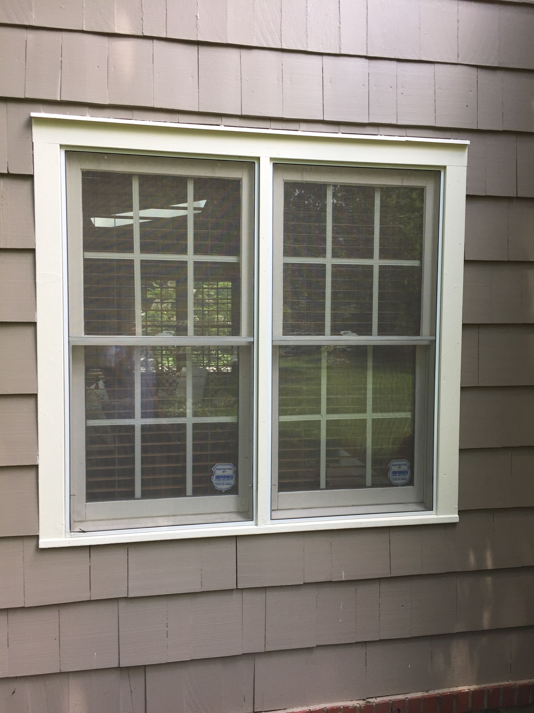 A double hung window on the side of a house with a white trim