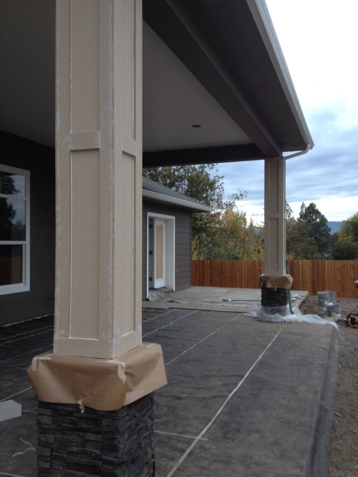 Beige porch columns with dark gray siding, a porch, and a cloudy sky.