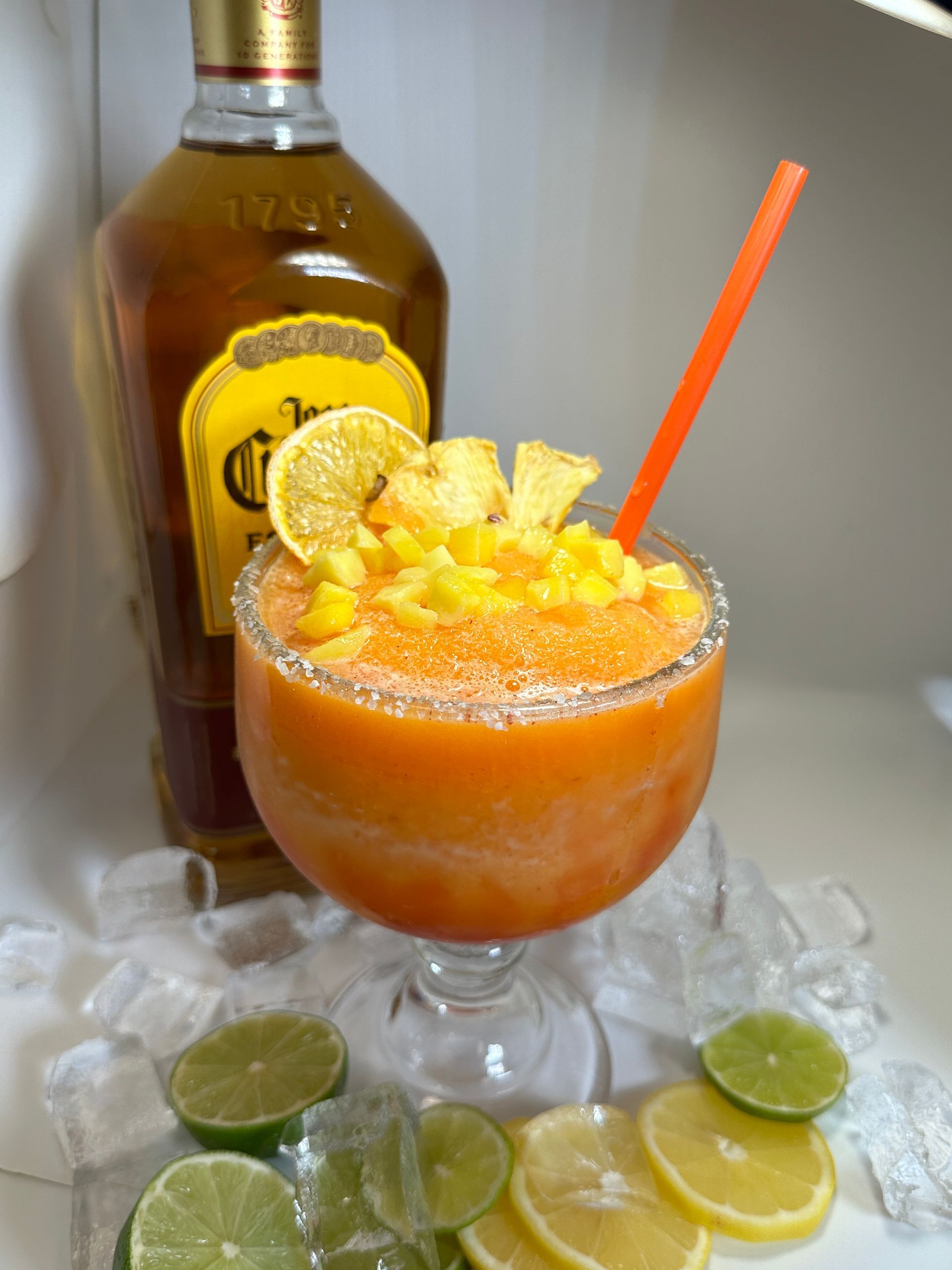Frozen orange cocktail with Crown Royal bottle, lime and lemon slices.