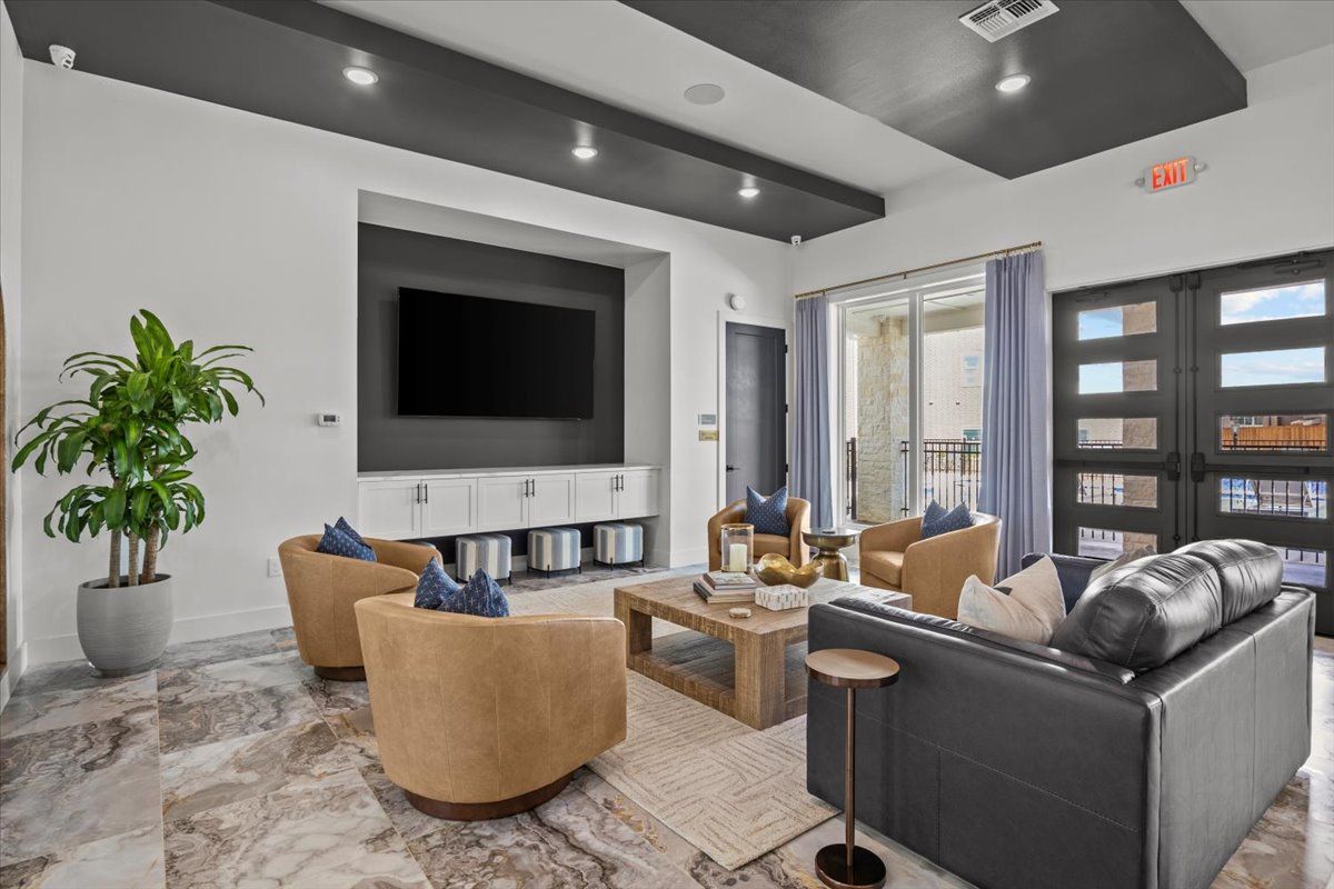 Modern living room with leather furniture, large TV, and open doors to a balcony.
