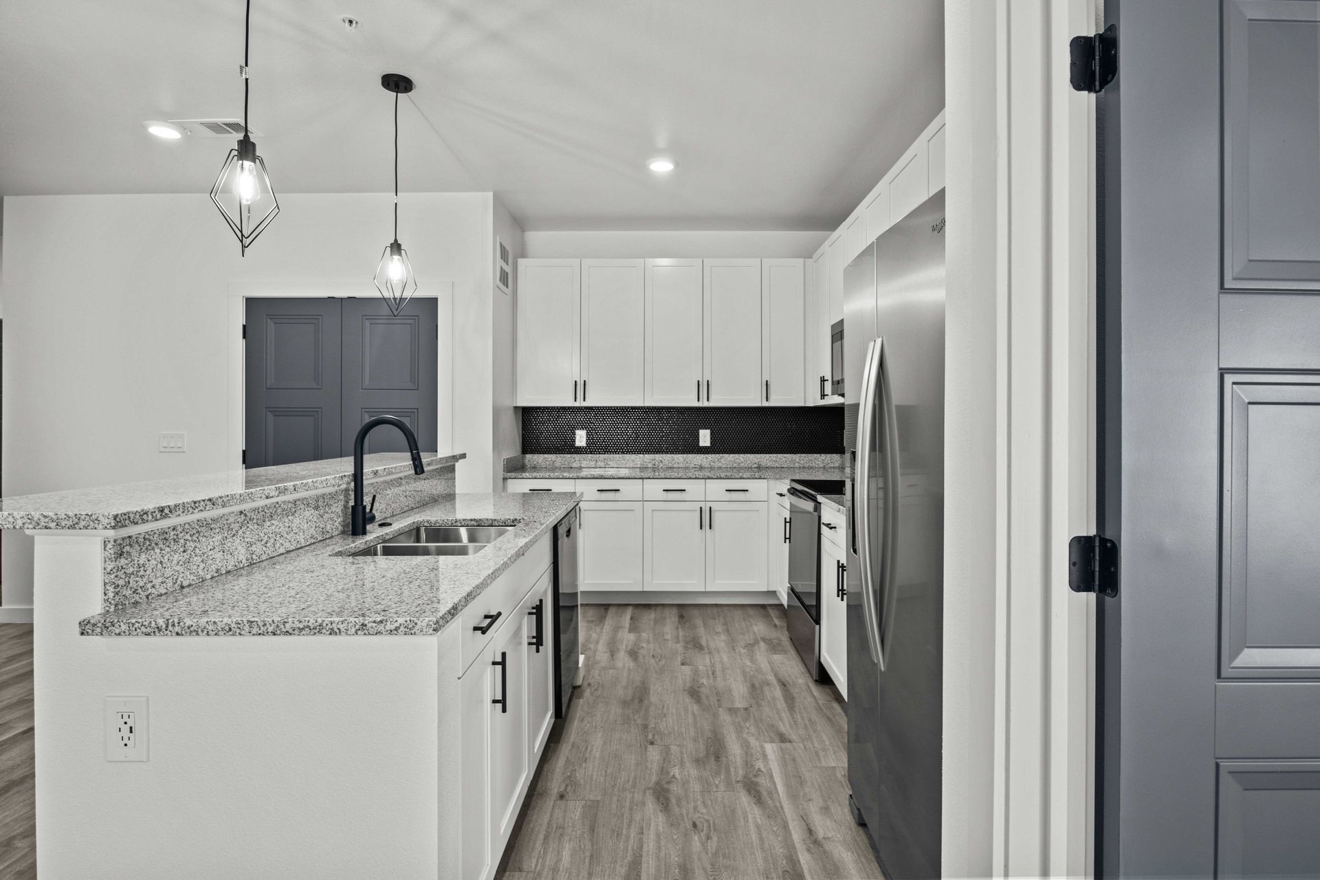 Modern kitchen with white cabinets, island, and stainless steel appliances.