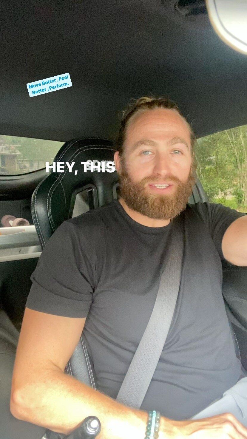 A man with a beard is sitting in the back seat of a car.