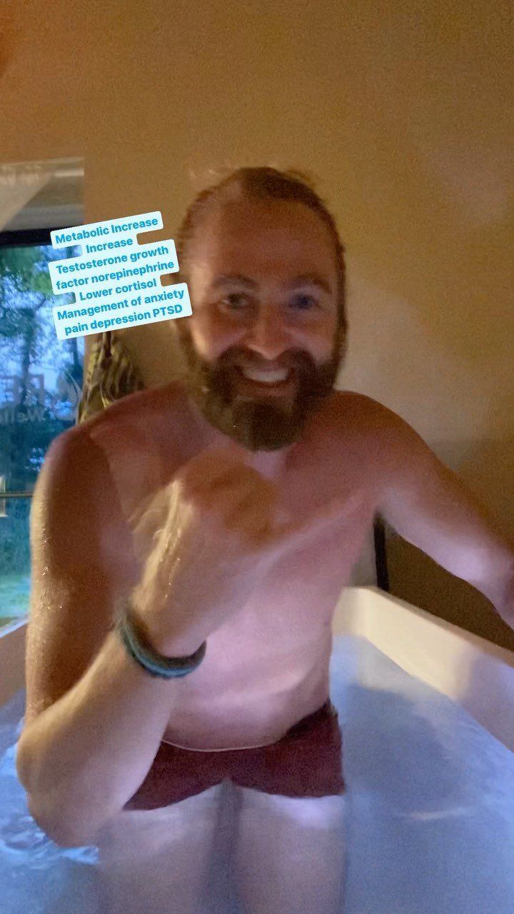 A shirtless man with a beard is sitting in a bathtub.