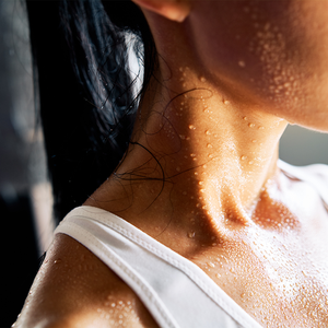 A close up of a woman 's neck and shoulder with sweat drops on it.