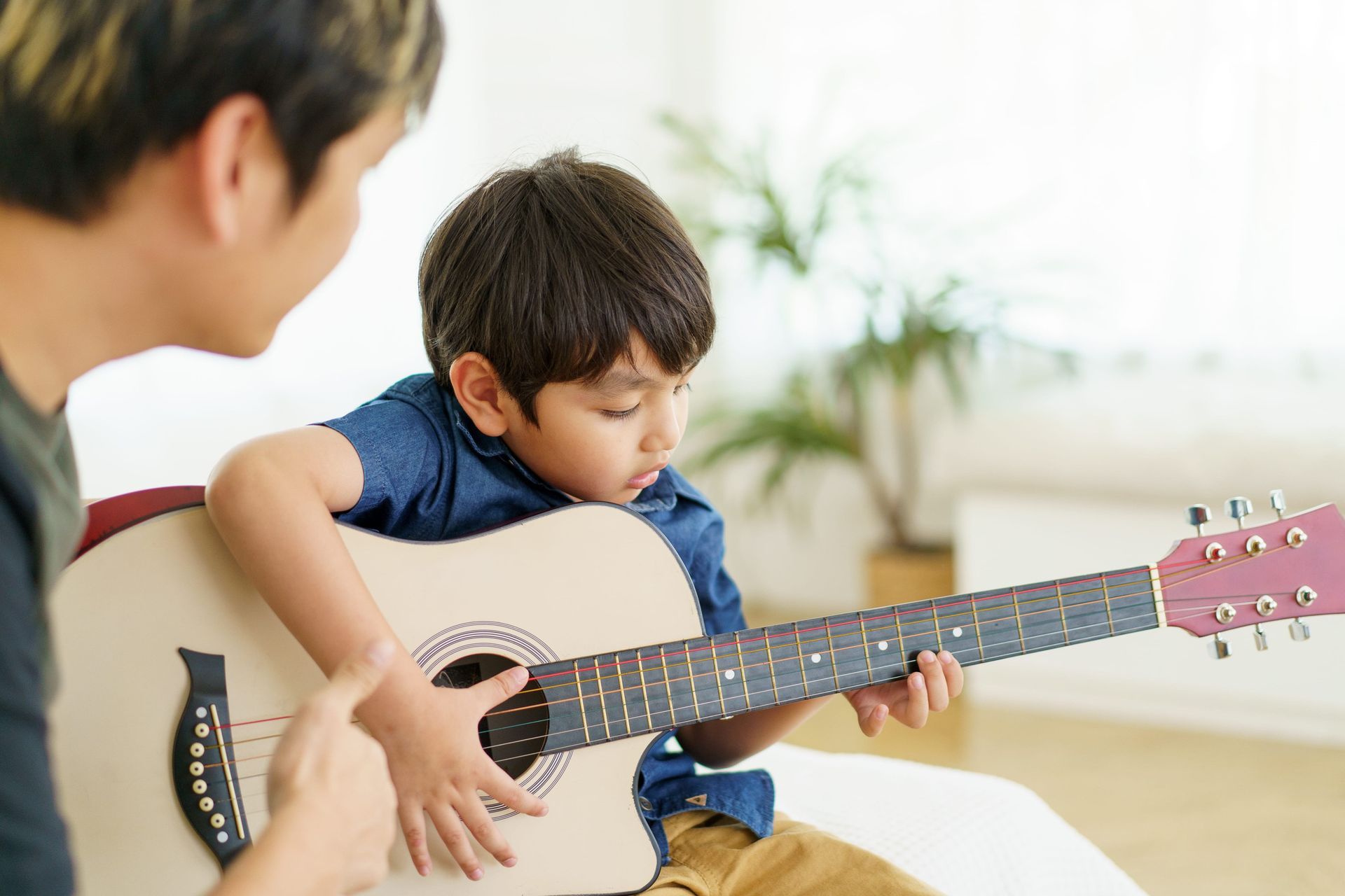 Young child learning to play guitar.