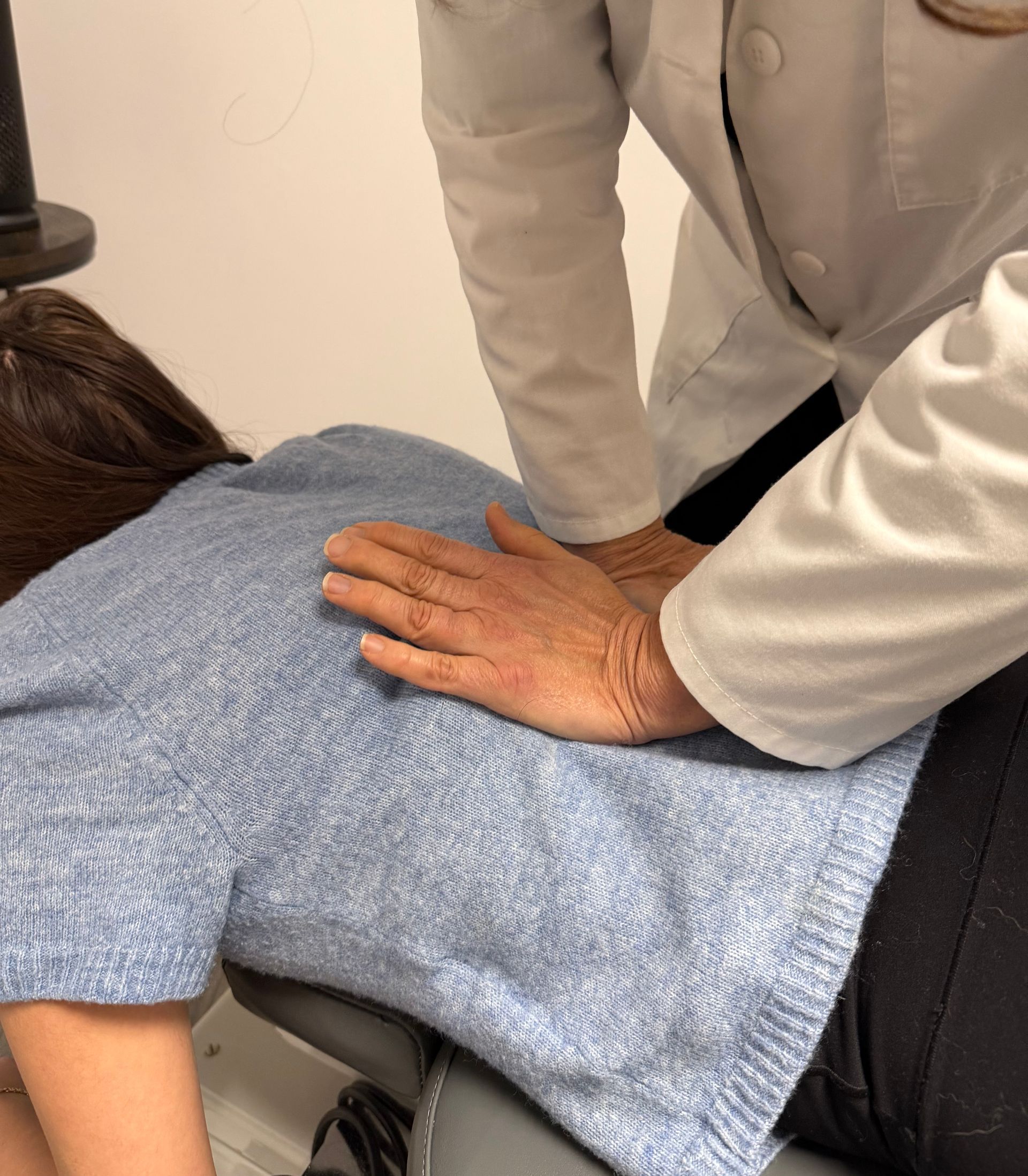 A healthcare worker assists a patient with arm movement in a medical office.