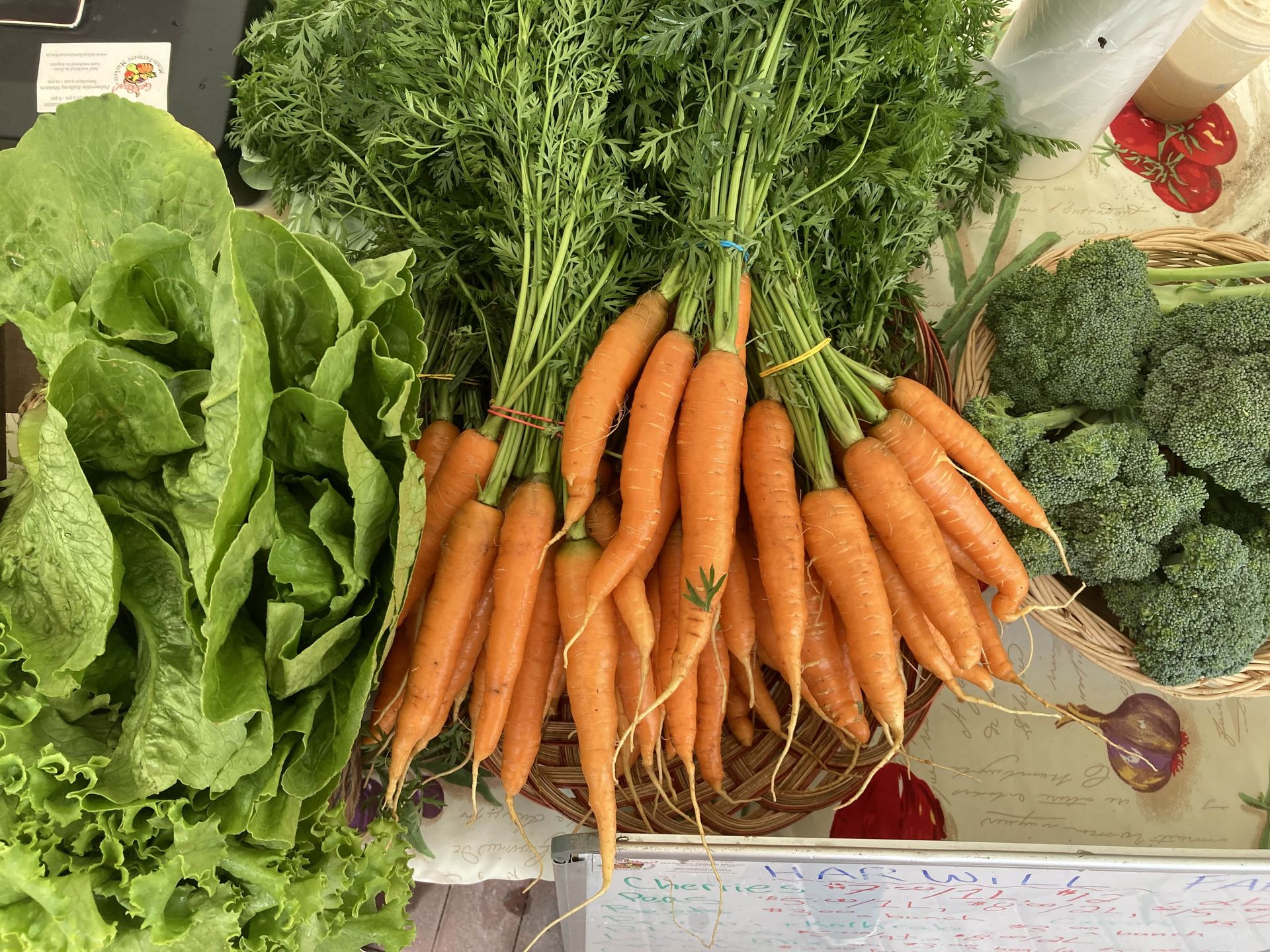 A bunch of carrots are sitting on a table next to lettuce and broccoli.