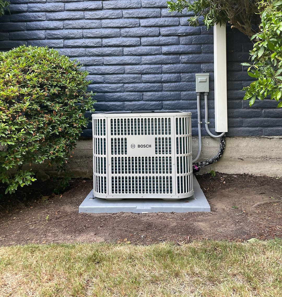 A large air conditioner is sitting outside of a brick building installed by Ready Energy Solutions.