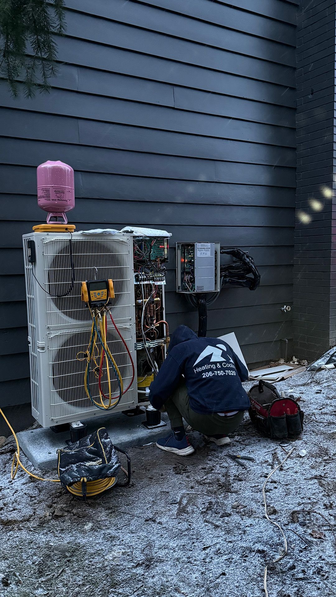 A Ready Energy Solutions Technician is working on an air conditioner outside of a house.
