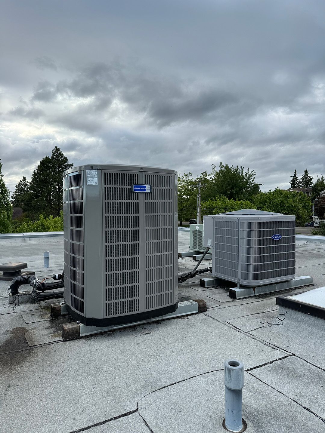 Two air conditioners are sitting on top of a roof installed by Ready Energy Solutions.