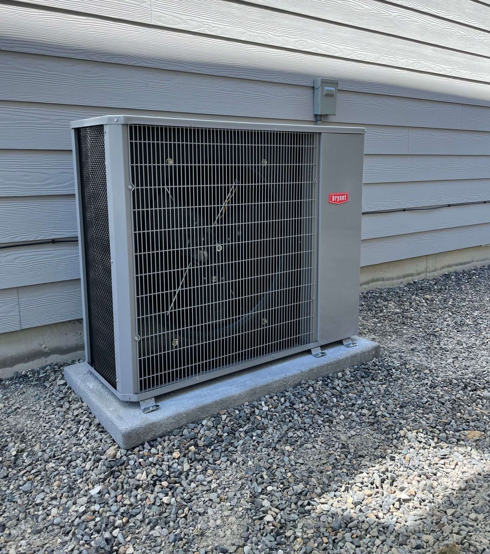 A large air conditioner is sitting outside of a house.