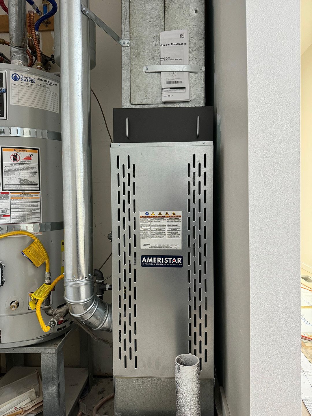 A heater is sitting next to a water heater in a room.