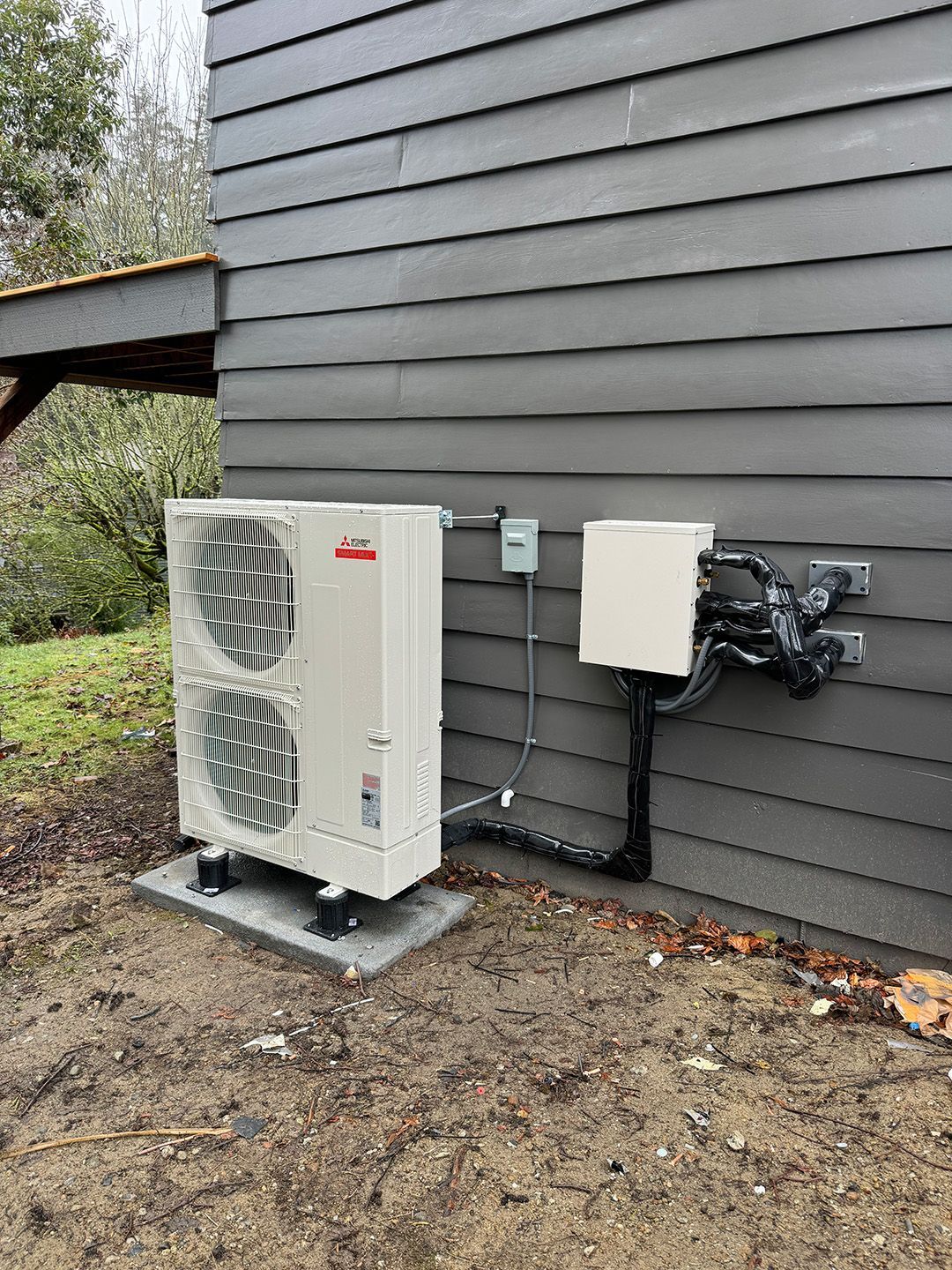 A white air conditioner is sitting on the side of a house installed by Ready Energy Solutions.