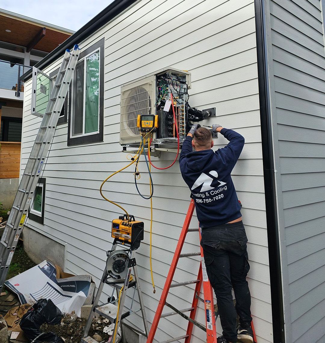 A Ready Energy Solutions Technician on a ladder is working on an air conditioner on the side of a house.
