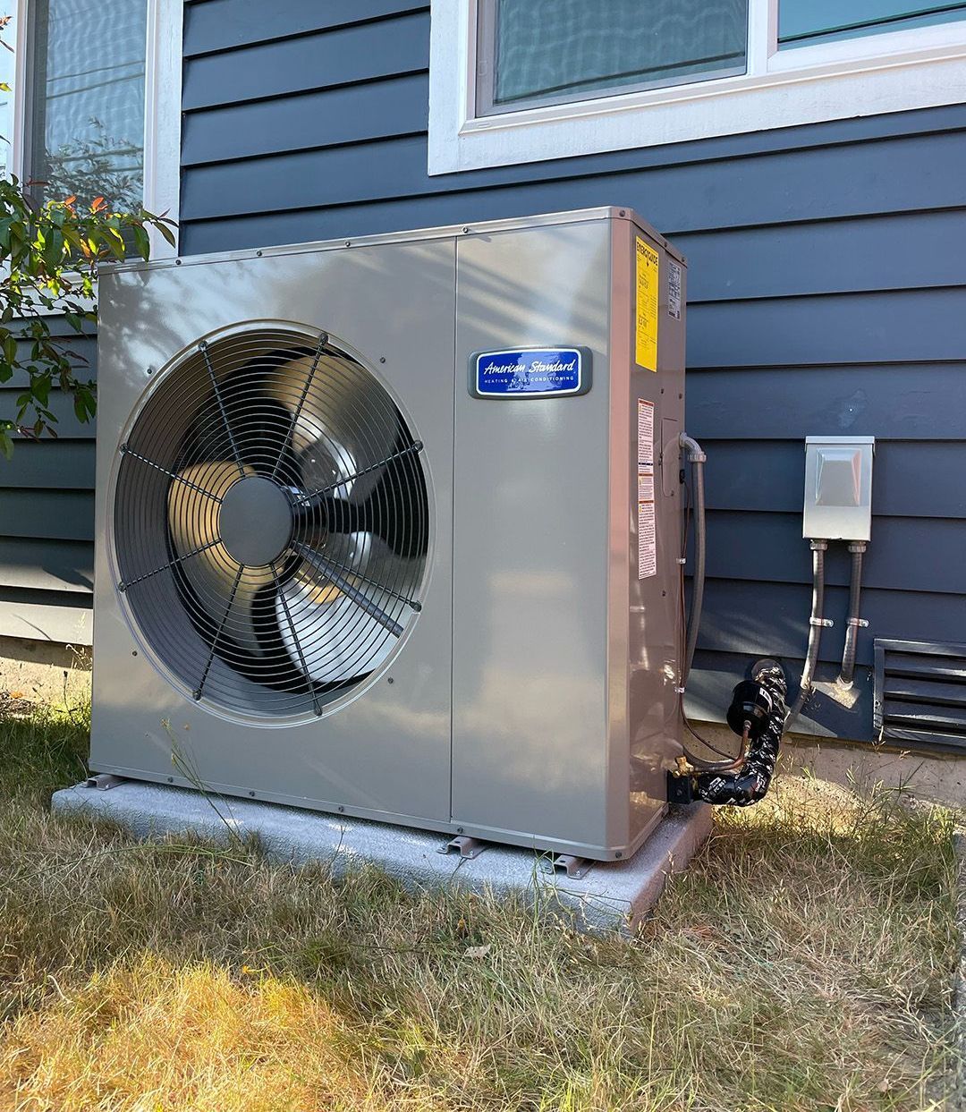 A large air conditioner is sitting on the side of a house.