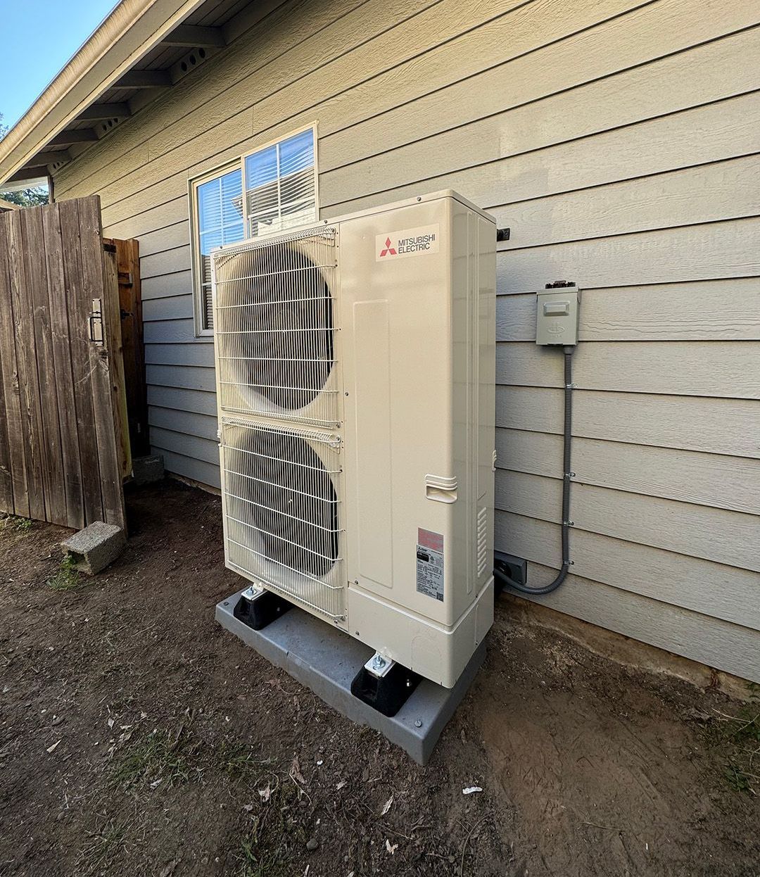 A large air conditioner is sitting on the side of a house installed by Ready Energy Solutions.