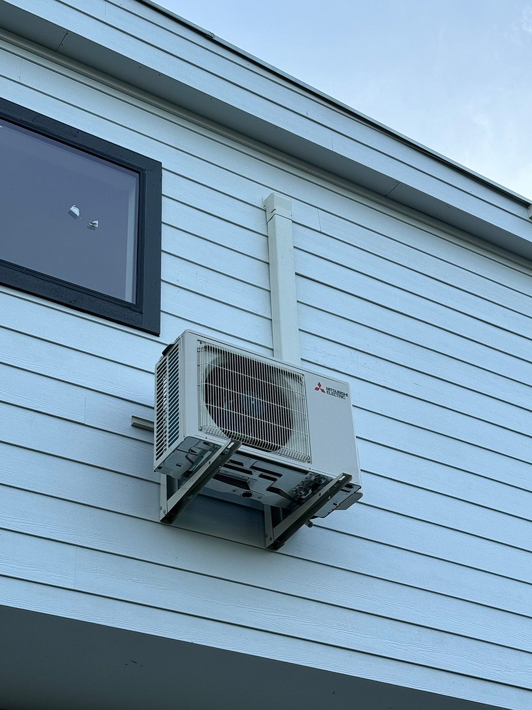 An air conditioner is mounted on the side of a house.