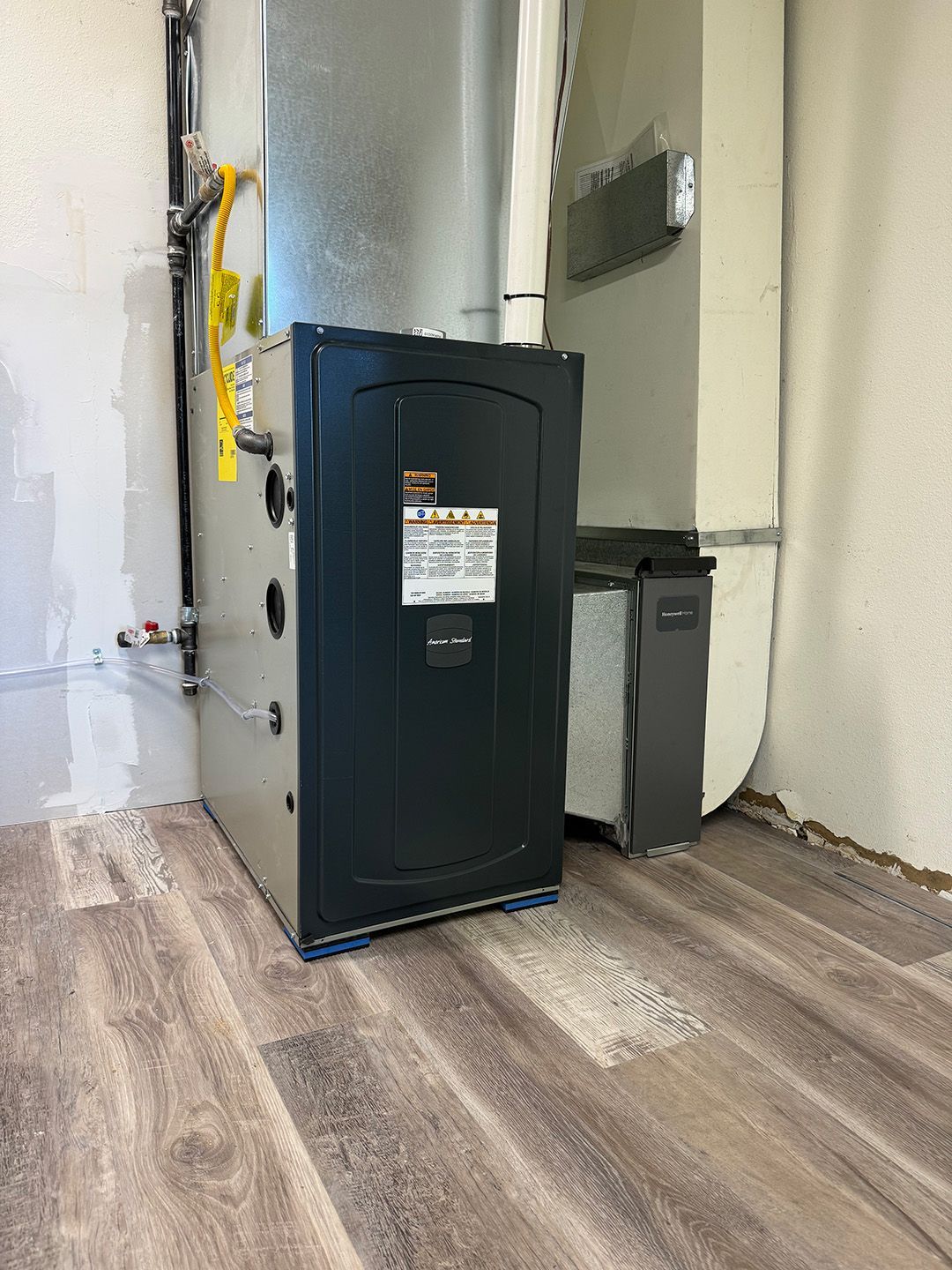 A furnace is sitting on a wooden floor in a room installed by Ready Energy Solutions.