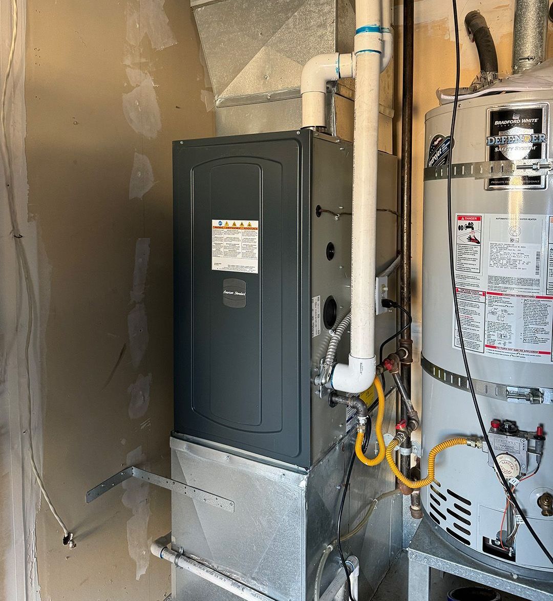 A water heater is sitting next to a furnace in a room installed by Ready Energy Solutions.