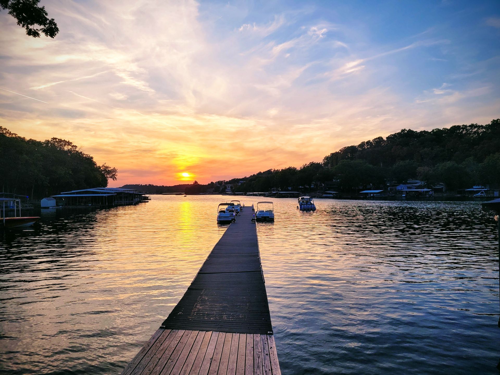A sunset over a lake with a dock in the foreground