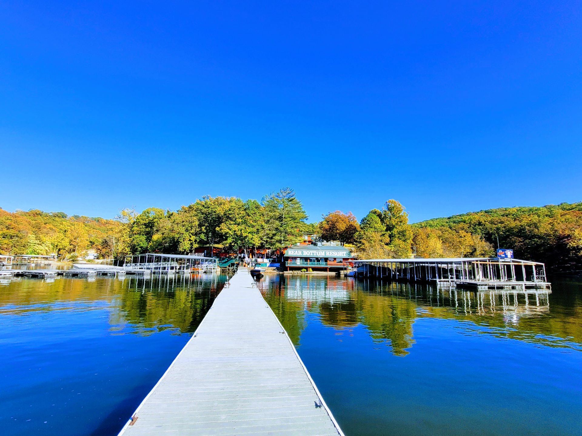 A dock leading to a lake with boats docked on it.