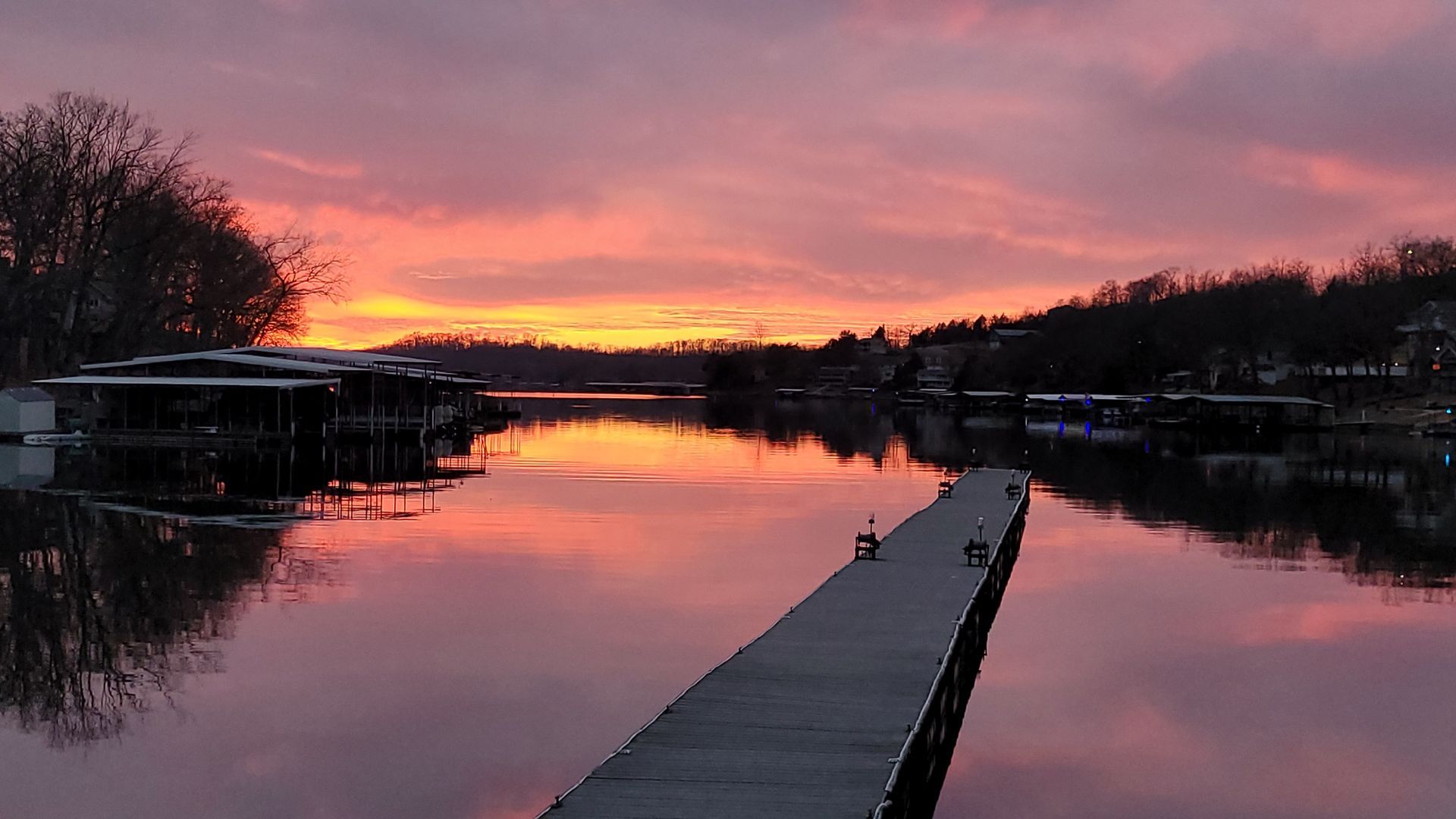A sunset over a lake with a dock in the foreground.