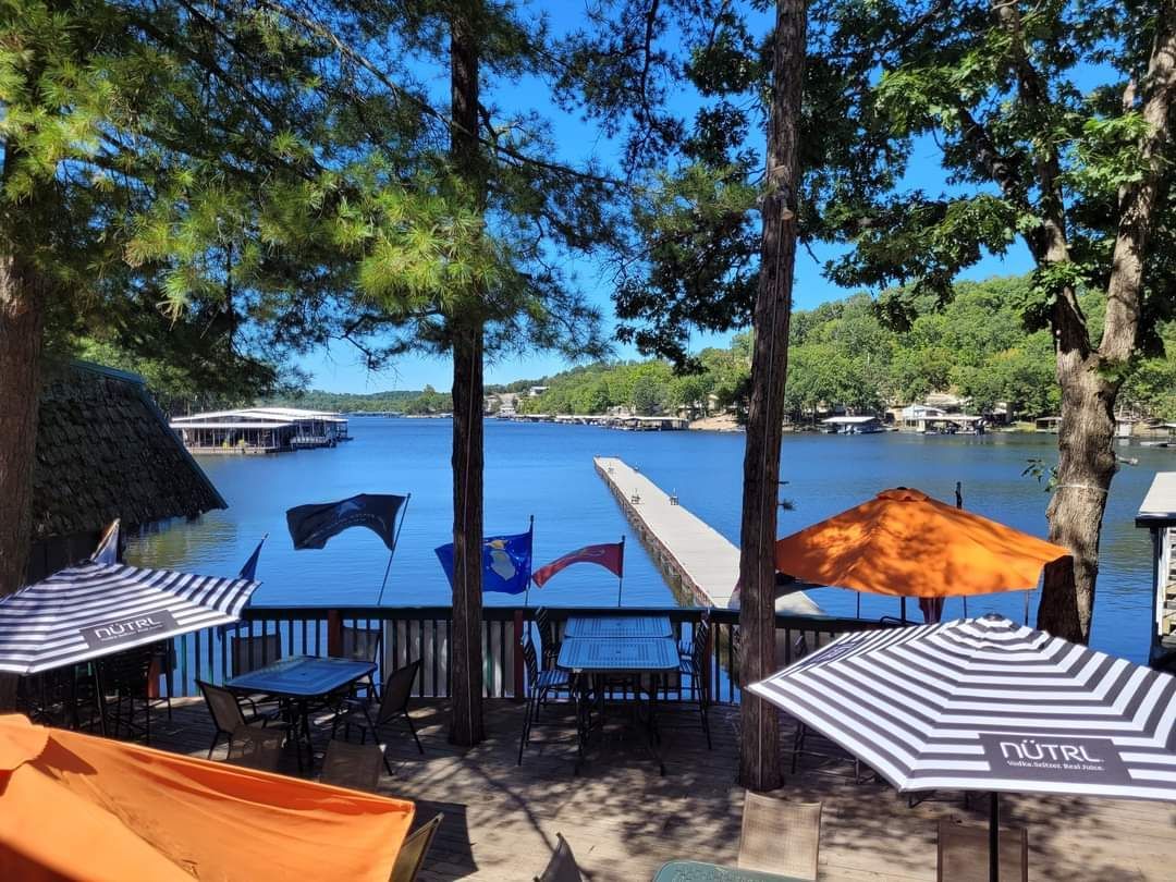 A view of a lake from a deck with tables and umbrellas
