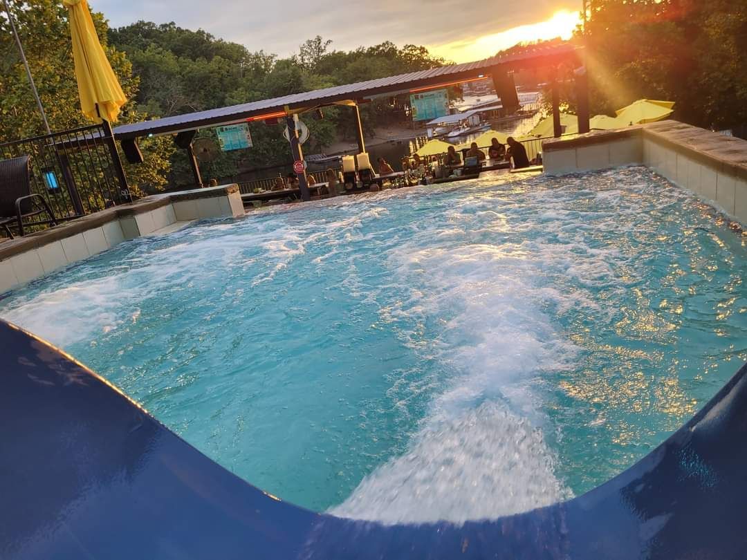 A swimming pool with a slide in it and a sunset in the background.